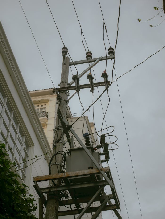 Vertical shot of an electric power pylon with cables against a cloudy sky.